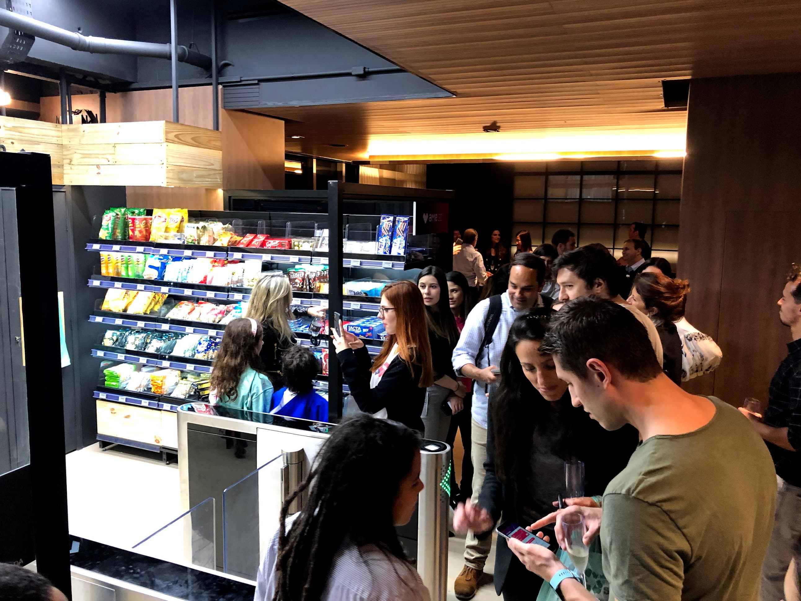 Crowd of attendees at the store opening event, browsing shelves and taking photos